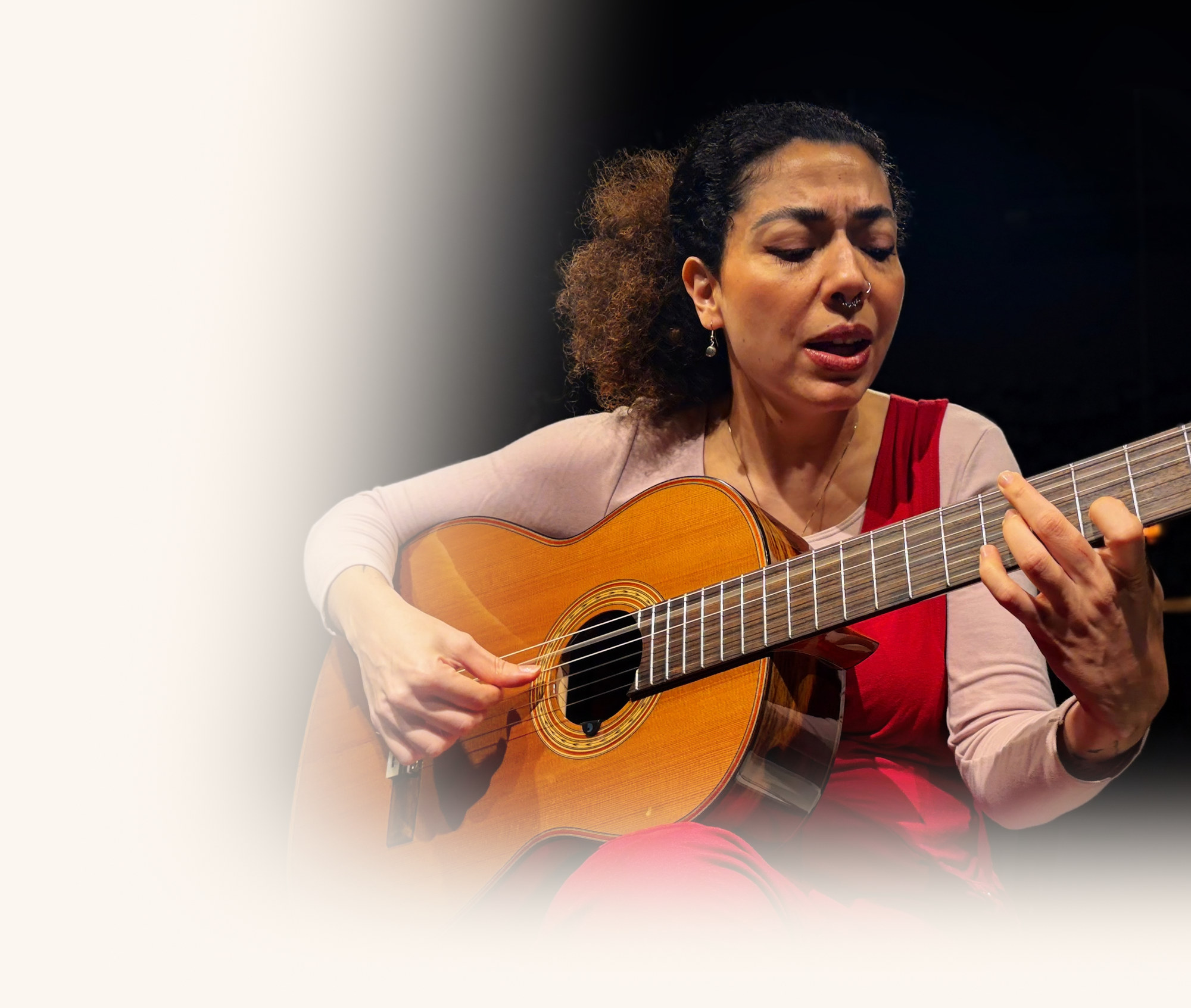 Vanessa Moreno cantando de olhos fechados enquanto toca violão